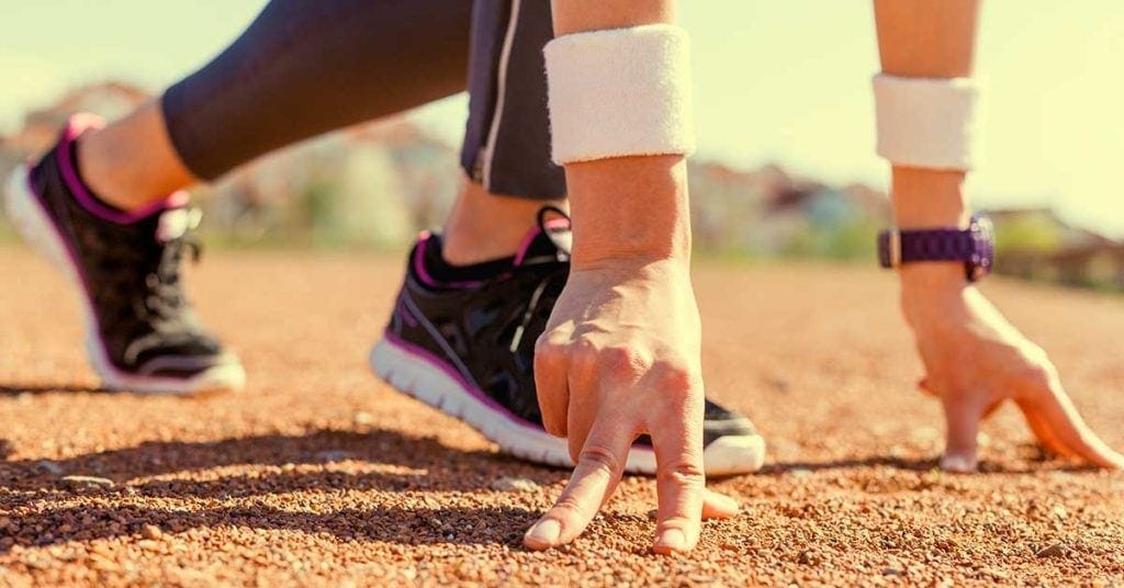 A runner with their hands on the floor getting ready to start a sprint