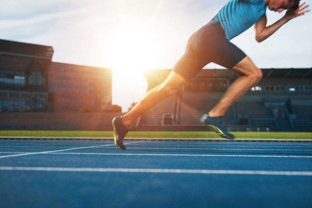 A man setting off to do a short sprint inside a stadium