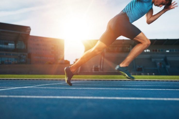 A man setting off to do a short sprint inside a stadium