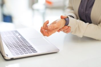 A woman stretching her writs as she works