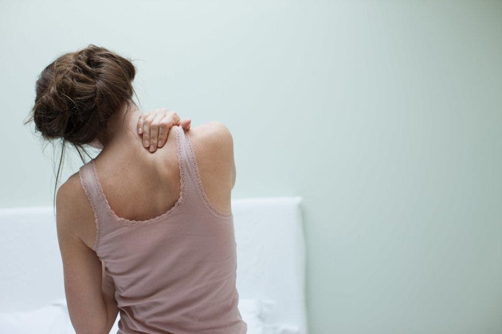 A woman massaging her own neck and back