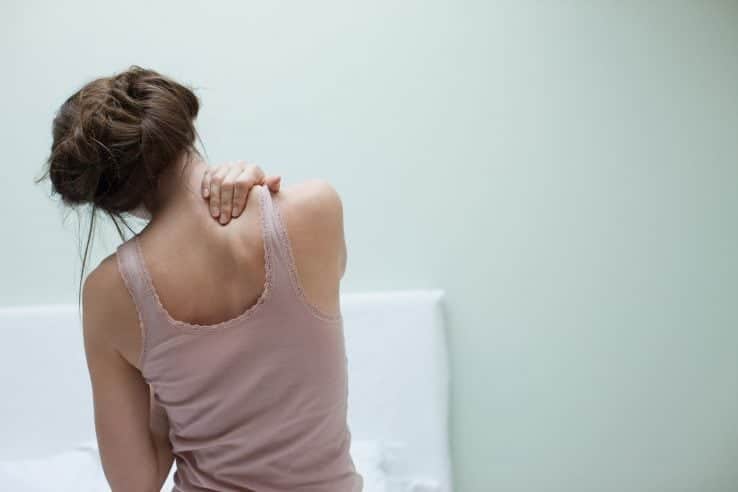 A woman massaging her own neck and back