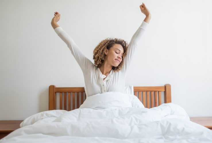 A woman yawning in bed as she wakes up