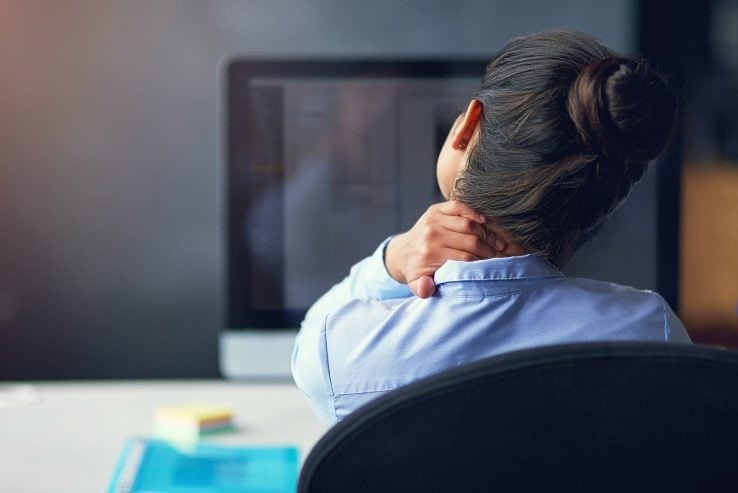 A woman sat at her desk with a sore neck