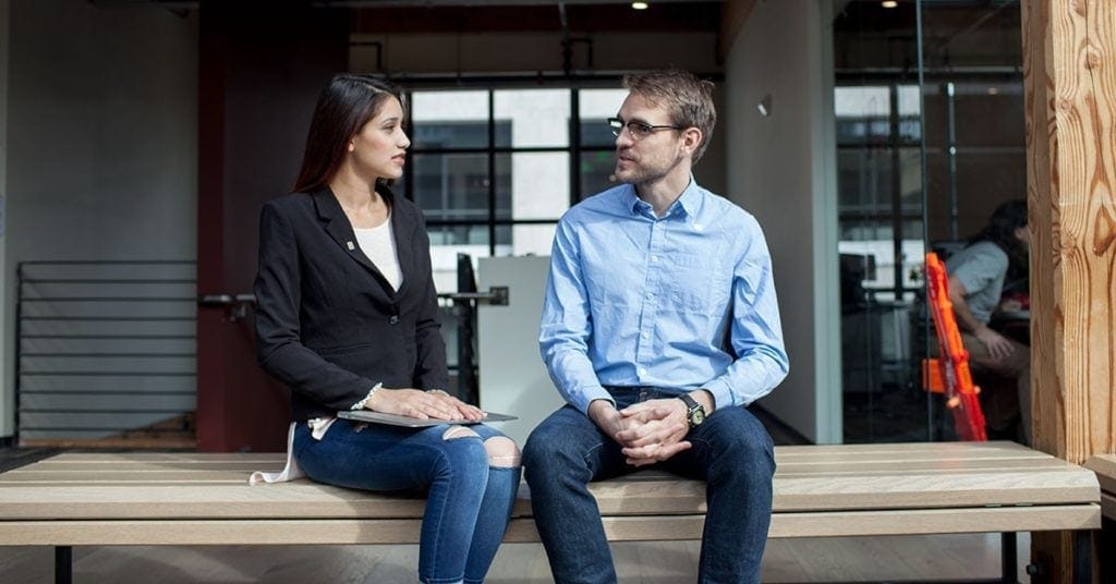 A man and a woman sat on a bench having a conversation