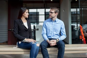 A man and a woman sat on a bench having a conversation