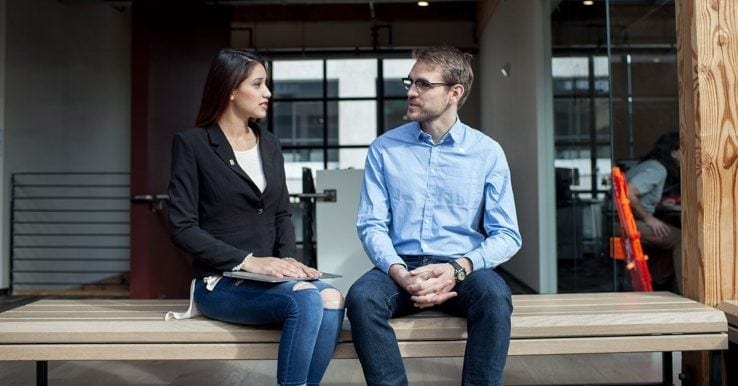 A man and a woman sat on a bench having a conversation