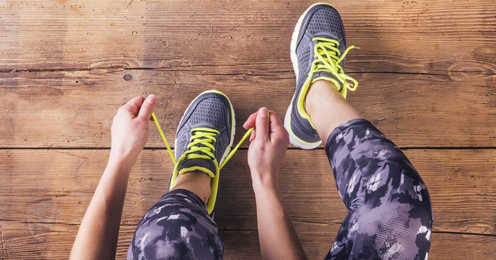 A close up of a woman typing up her running shoes