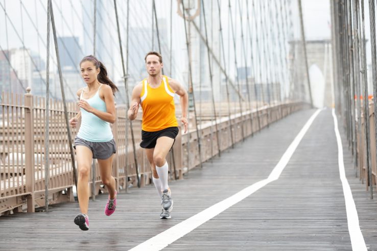 A couple running together over a bridge
