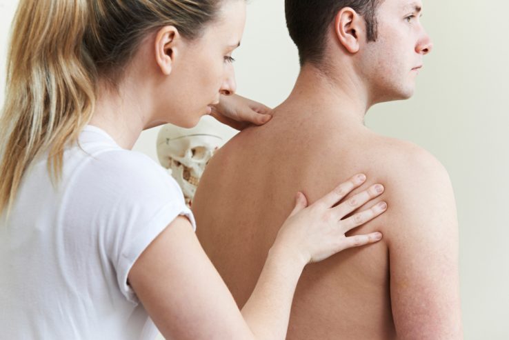 A female doctor checking the strentgh of a mans back