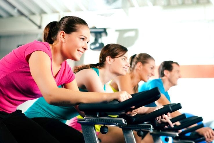 A group of women all exercising together on exercise bikes
