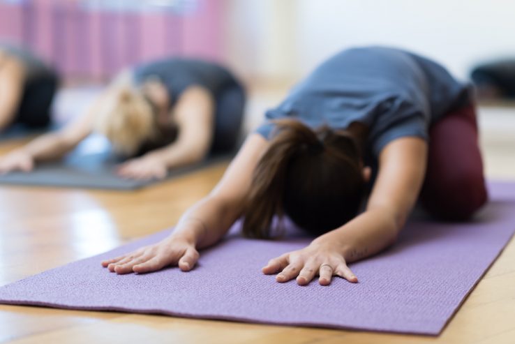 A lady doing a childs pose in a yoga class
