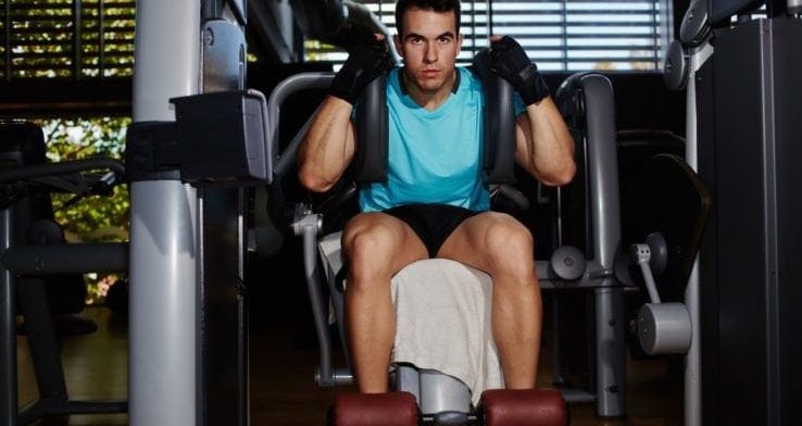 A man about to use a ab crunch machine in the gym