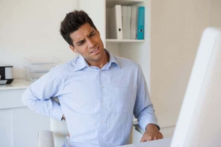 A man in his office who has a lower bad back