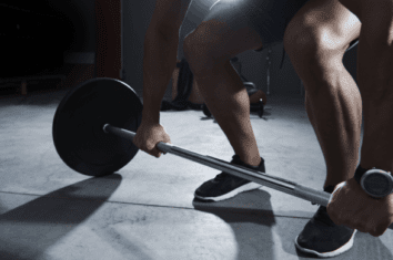 A man in the gym about to lift a barbell weight
