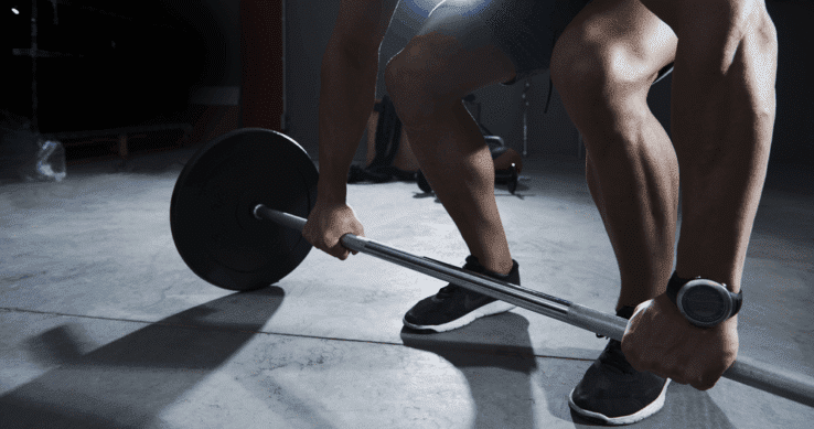 A man in the gym about to lift a barbell weight