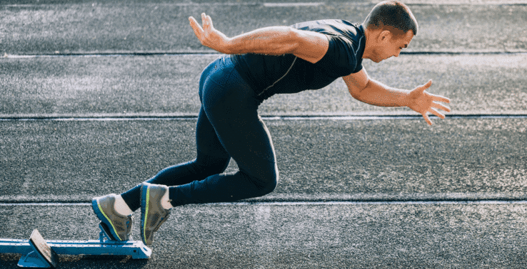 A man setting off from the running blocks