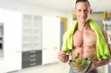 A shirtless man eating salad before he goes to exercise