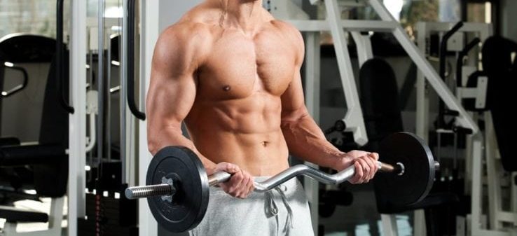 A shirtless man in the gym using a EZ curl bar