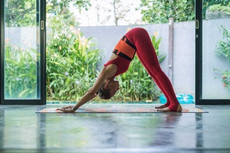 A woman doing a downward dog pose in her home
