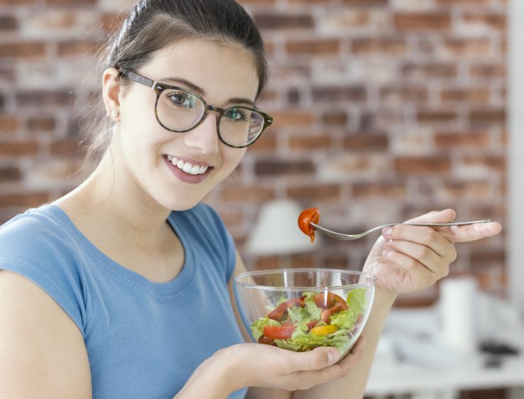 A woman eating a healthy bowl of salad and vegetables