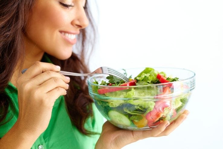 A woman eating a healthy bowl of salad