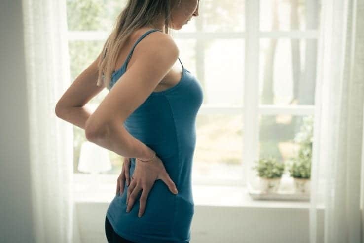 A woman holding her lower back as she struggles with the pain