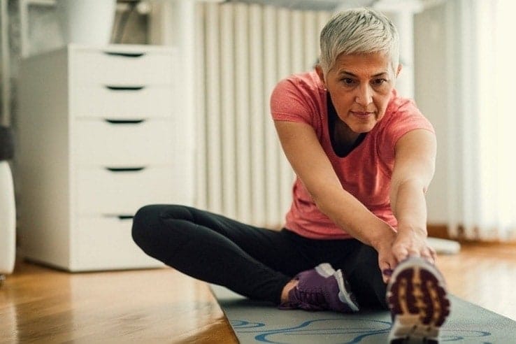 A woman stretching out on her yoga mat at home