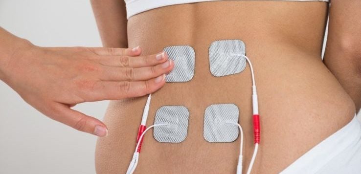 A woman using a electrical muscle stimulation on her lower back