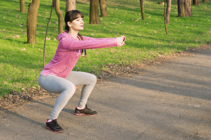 A woman warming up for her run by doing squats