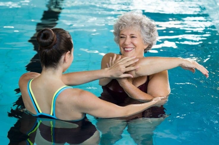 An elder lady stretching before she does aqua therapy