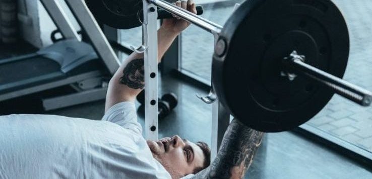 An overweight man bench pressing in the gym