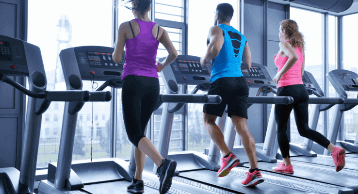 Multiple people running on treadmills side by side