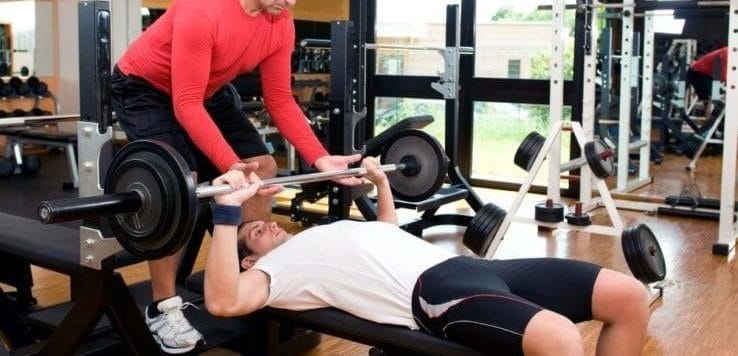 Two men bench pressing together in the gym