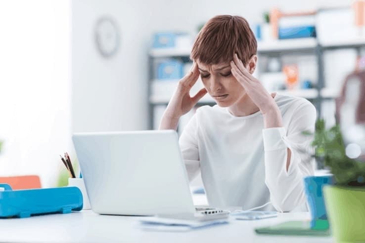 a woman sat her desk looking very stressed