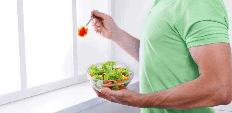 a man eating a salad near a window