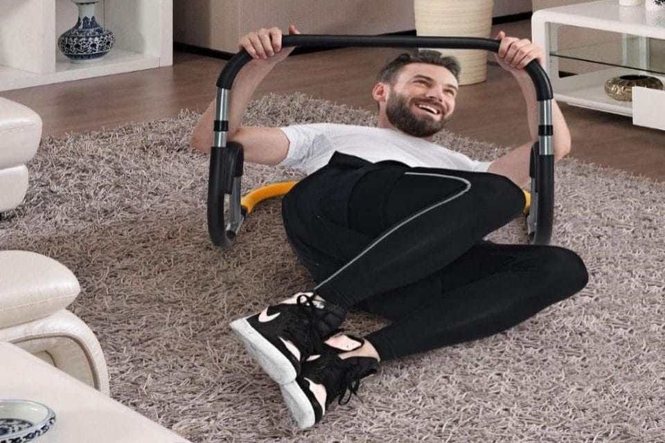 a man exercising with an ab machine on a rug