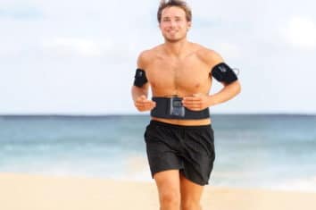 a man using an ab toning belt while he runs on the beach