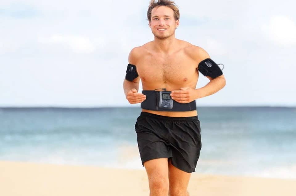 a man using an ab toning belt while he runs on the beach