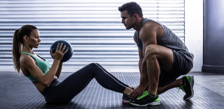 a woman doing sit-ups with a personal trainer