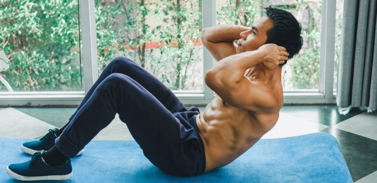 asian man doing sit-ups near a window