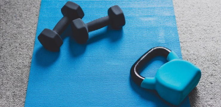 dumbbells and kettlebells on a blue mat on the floor