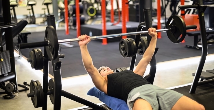 man training doing bench press in a gym